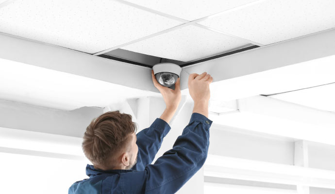 Person installing a security camera on the ceiling